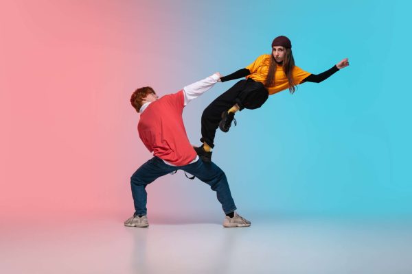 Boy And Girl Dancing Hip Hop In Stylish Clothes On Gradient Background At Dance Hall In Neon Light.